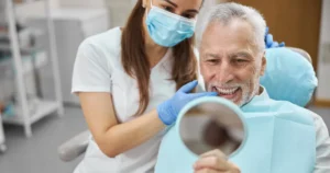 Man Looking At Dental Implants in Mirror